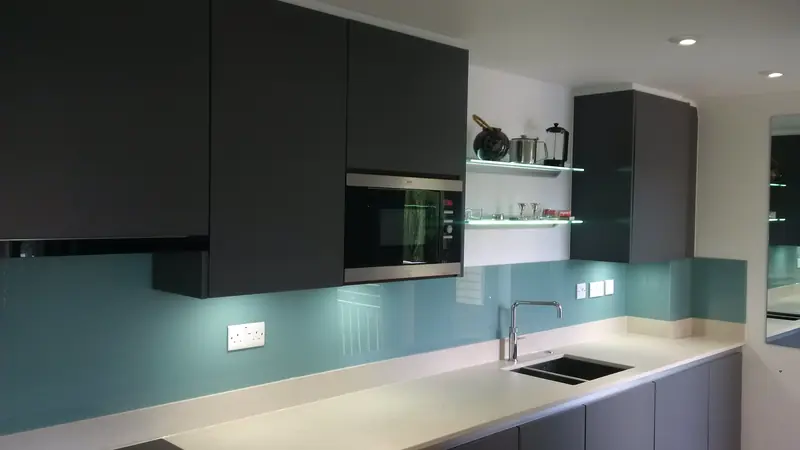 Modern kitchen with anthracite grey units and teal glass splashback in Cobham Surrey